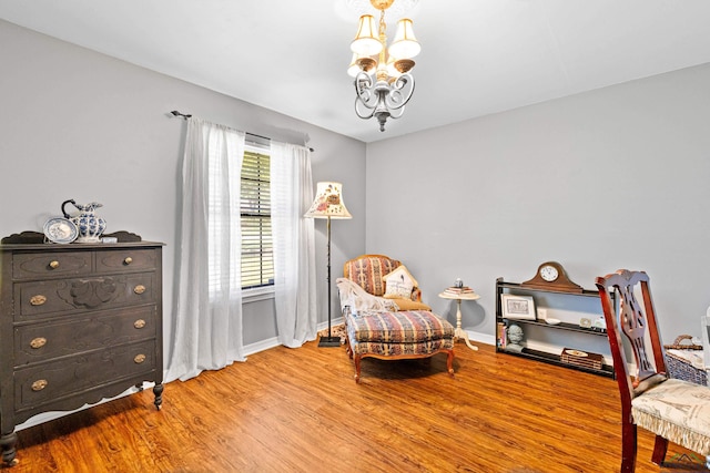 sitting room with a chandelier, wood finished floors, and baseboards