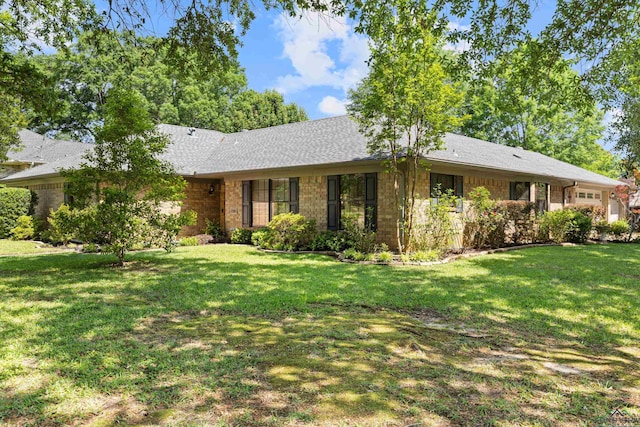 ranch-style house featuring a front yard, brick siding, and an attached garage
