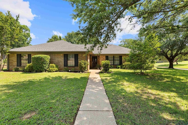 ranch-style home with a shingled roof, brick siding, and a front yard