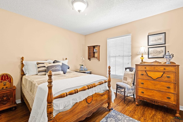 bedroom with a textured ceiling, baseboards, and wood finished floors