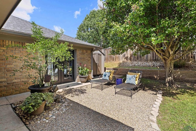 view of patio / terrace with a fenced backyard, an outdoor structure, a storage unit, and french doors