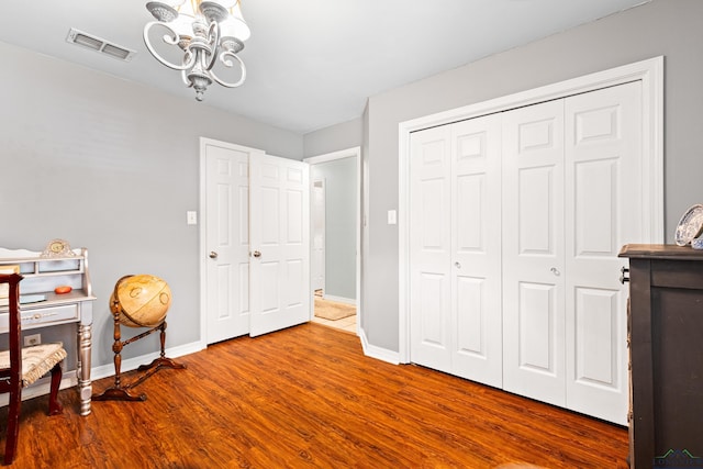 bedroom with wood finished floors, a closet, a notable chandelier, visible vents, and baseboards