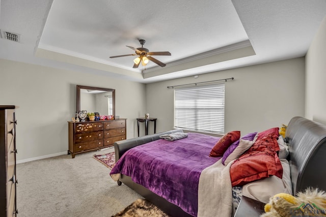 carpeted bedroom featuring a textured ceiling, visible vents, baseboards, a tray ceiling, and crown molding