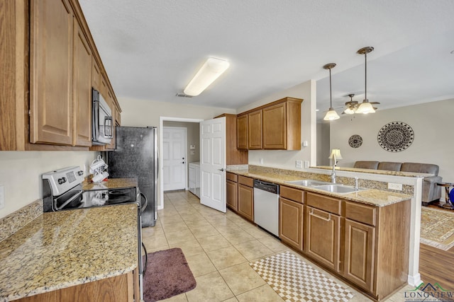 kitchen with brown cabinets, open floor plan, a peninsula, stainless steel appliances, and a sink