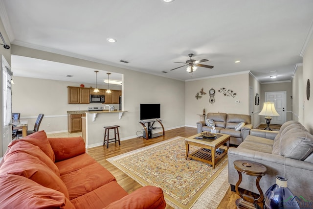 living area featuring light wood-style floors, baseboards, crown molding, and recessed lighting