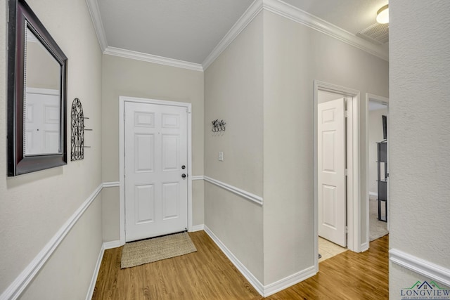 foyer featuring ornamental molding, wood finished floors, visible vents, and baseboards