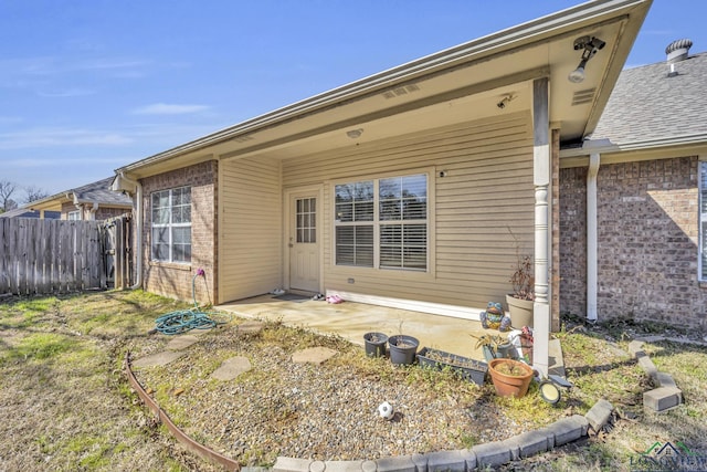 rear view of property featuring brick siding, fence, and a patio