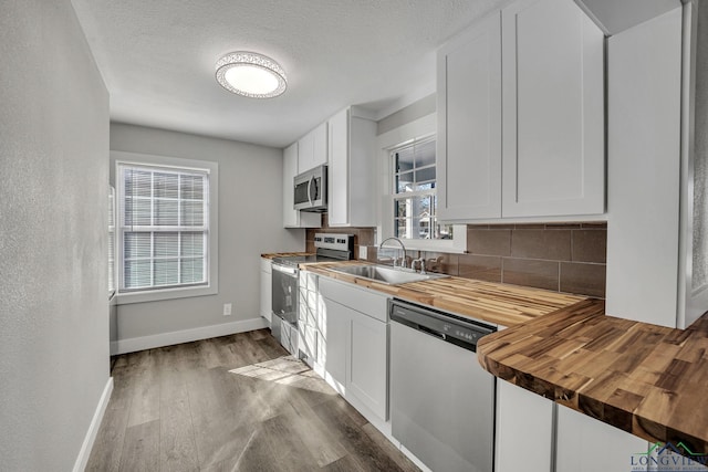 kitchen featuring white cabinets, butcher block counters, sink, and appliances with stainless steel finishes