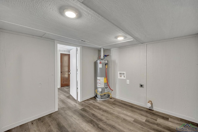 basement with a textured ceiling, gas water heater, and hardwood / wood-style flooring