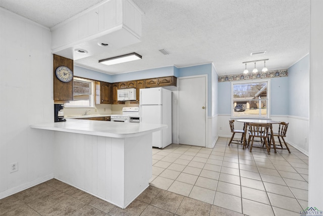 kitchen with white appliances, light countertops, a wealth of natural light, and a textured ceiling