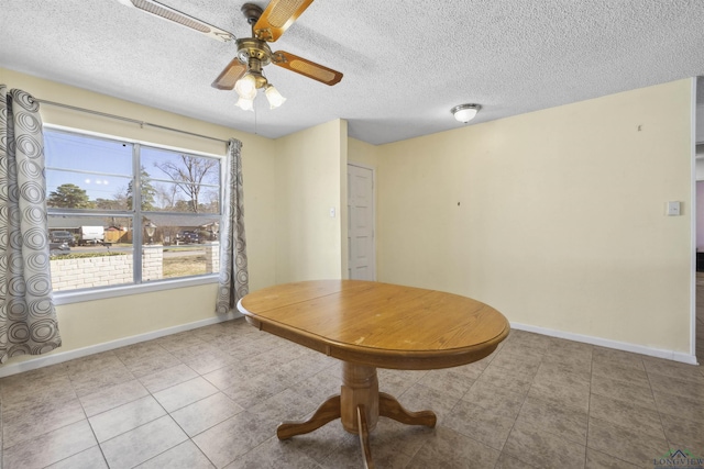 unfurnished dining area featuring tile patterned flooring, ceiling fan, baseboards, and a textured ceiling