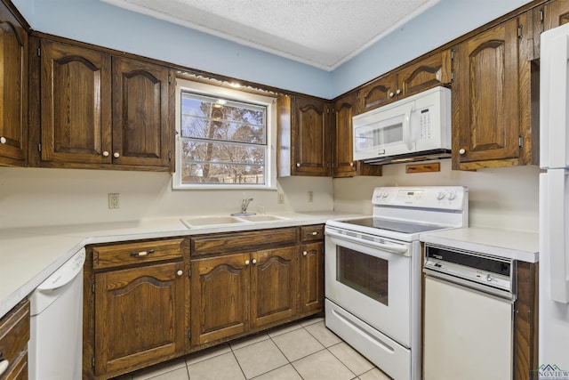 kitchen with a textured ceiling, white appliances, light countertops, and a sink