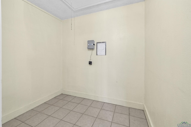 empty room with light tile patterned floors, baseboards, a textured ceiling, and attic access