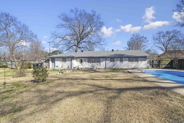 back of house featuring brick siding, a fenced in pool, fence, and a lawn