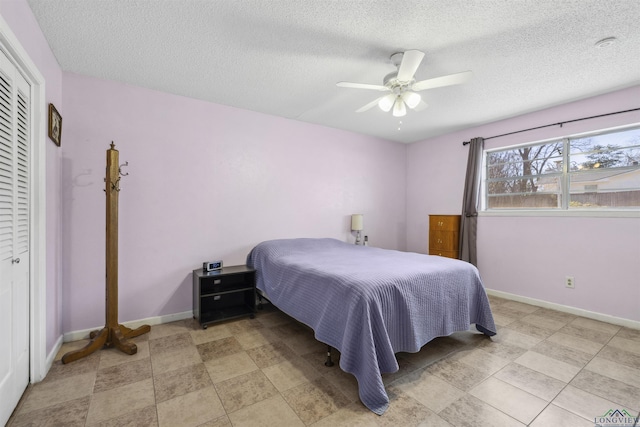 bedroom featuring a textured ceiling, baseboards, a closet, and ceiling fan