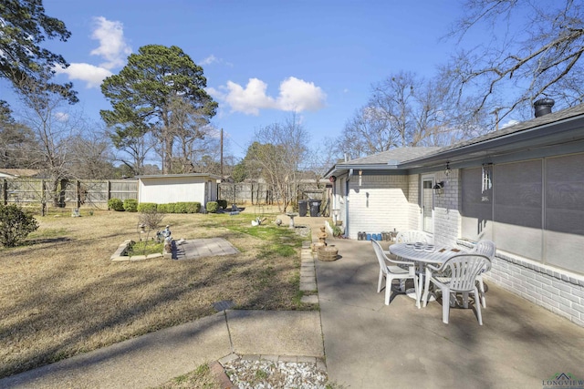 view of yard featuring a patio, an outbuilding, outdoor dining space, and fence