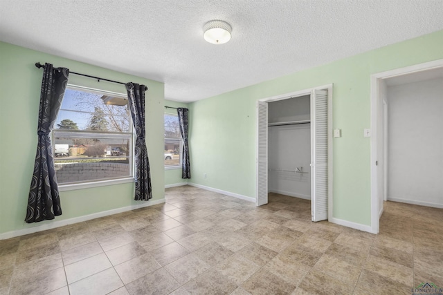 unfurnished bedroom featuring a closet, a textured ceiling, and baseboards