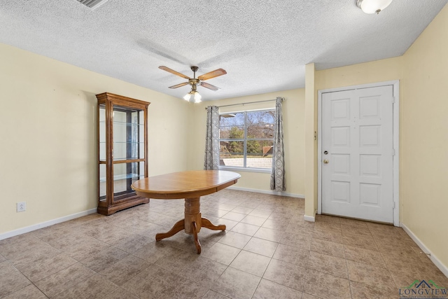 unfurnished dining area featuring light tile patterned floors, a ceiling fan, baseboards, and a textured ceiling