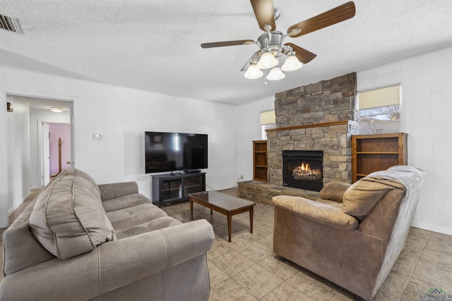 living area with visible vents, a textured ceiling, a fireplace, and a ceiling fan