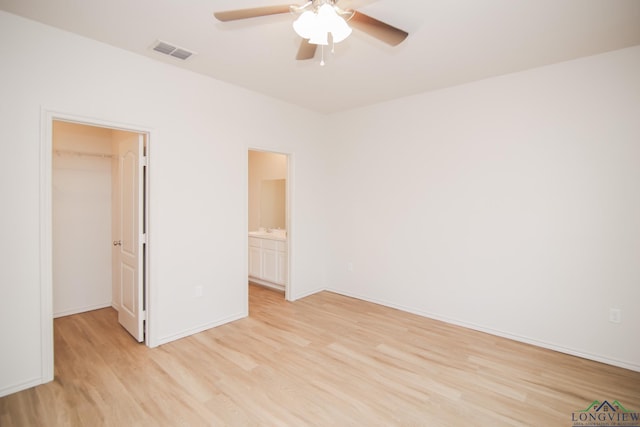 1146 Mission Creek Dr, Longview, TX 75601 - unfurnished bedroom featuring light wood-style floors, a walk in closet, a closet, ceiling fan, and ensuite bathroom