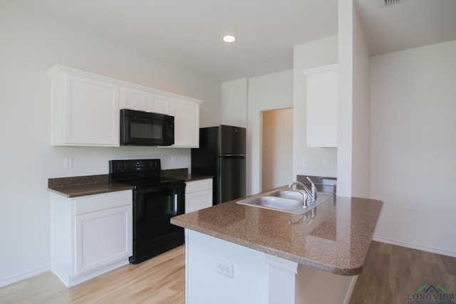 1146 Mission Creek Dr, Longview, TX 75601 - kitchen with black appliances, light wood-style flooring, white cabinets, recessed lighting, and dark stone counters