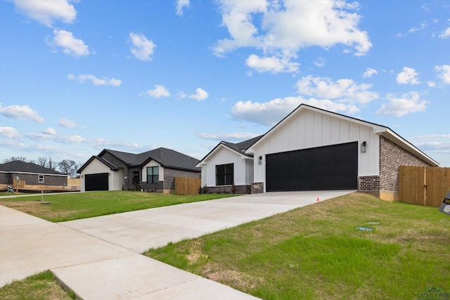 modern inspired farmhouse with concrete driveway, an attached garage, fence, board and batten siding, and a front yard