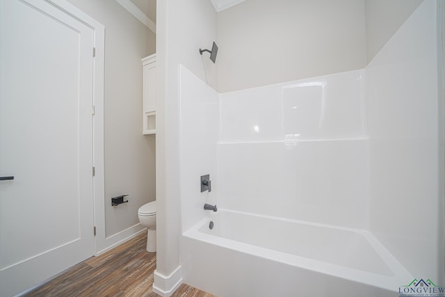 bathroom featuring wood-type flooring, shower / washtub combination, and toilet