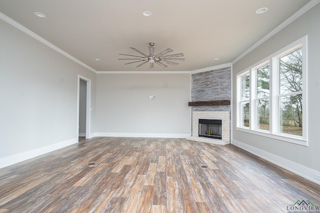 unfurnished living room featuring a brick fireplace, hardwood / wood-style flooring, ornamental molding, and ceiling fan