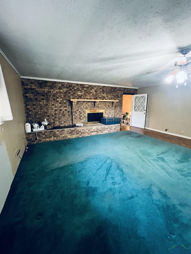 unfurnished living room with ceiling fan, brick wall, carpet, and a textured ceiling