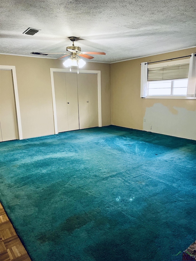 unfurnished bedroom with two closets, a textured ceiling, and ceiling fan