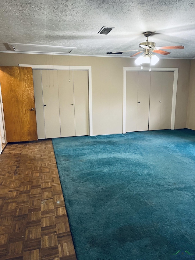 unfurnished bedroom with a textured ceiling, dark parquet floors, and ceiling fan