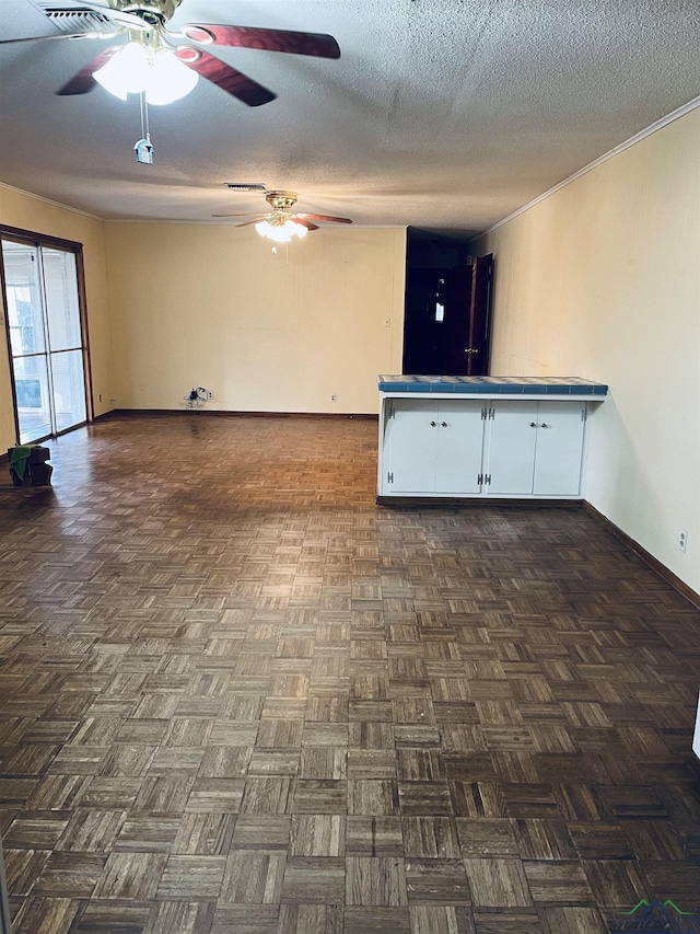 interior space with ceiling fan, dark parquet flooring, and a textured ceiling