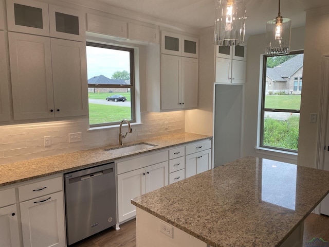 kitchen with white cabinetry, sink, stainless steel dishwasher, backsplash, and pendant lighting