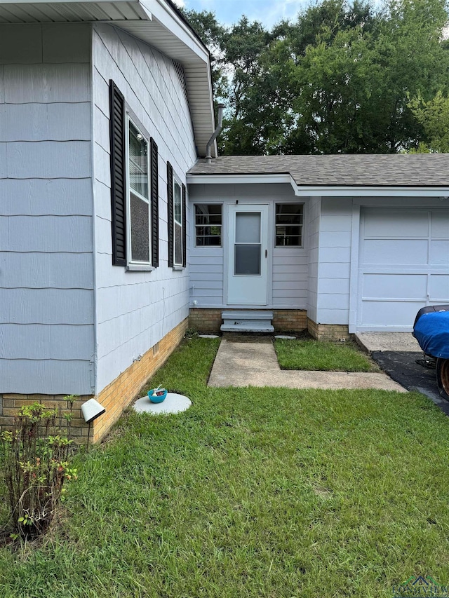 view of exterior entry featuring a yard and a garage