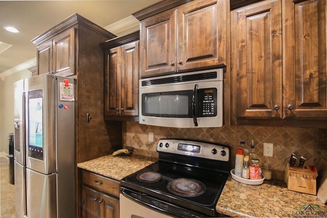 kitchen featuring dark brown cabinetry, appliances with stainless steel finishes, light stone counters, backsplash, and ornamental molding
