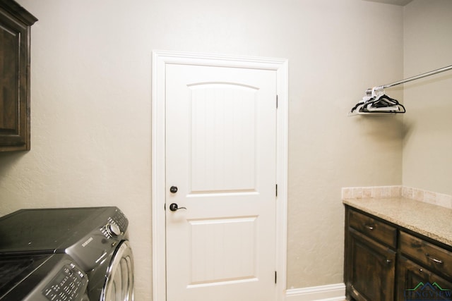 washroom featuring baseboards, washing machine and dryer, and cabinet space
