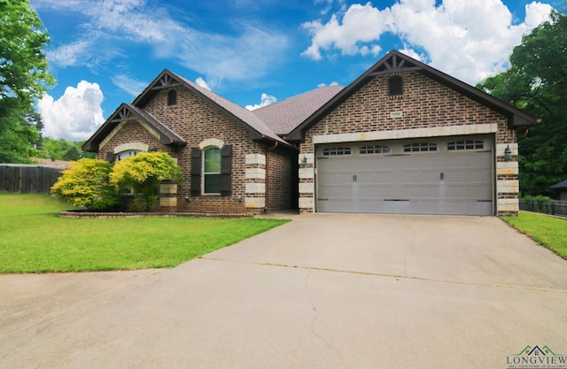 craftsman house with brick siding, an attached garage, a front yard, and concrete driveway