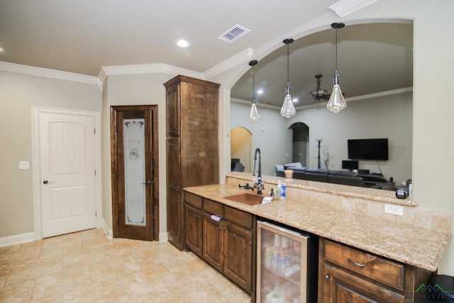 kitchen featuring light stone counters, a sink, beverage cooler, arched walkways, and visible vents