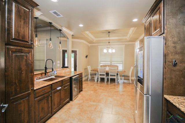 kitchen featuring visible vents, appliances with stainless steel finishes, dark brown cabinets, a sink, and a tray ceiling
