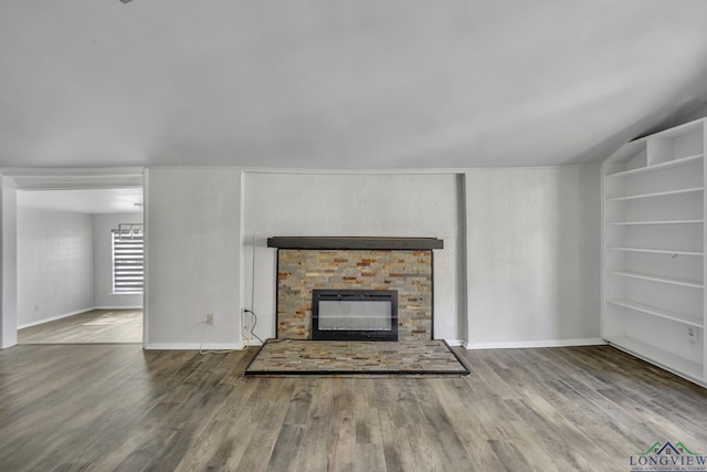 585 Naples Dr, Omaha, TX 75571 - unfurnished living room featuring baseboards, built in features, a glass covered fireplace, and wood finished floors