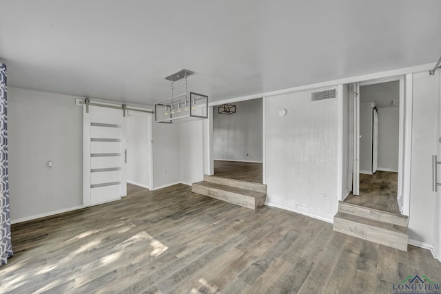 585 Naples Dr, Omaha, TX 75571 - unfurnished living room with wood finished floors, baseboards, a barn door, and visible vents