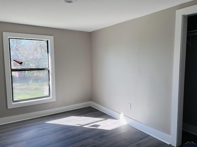 empty room with dark hardwood / wood-style floors and plenty of natural light