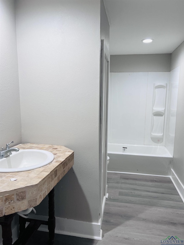 full bathroom featuring sink, washtub / shower combination, wood-type flooring, and toilet