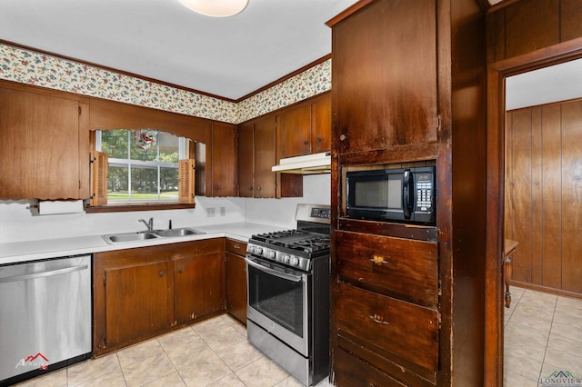 kitchen featuring wood walls, sink, light tile patterned floors, and appliances with stainless steel finishes