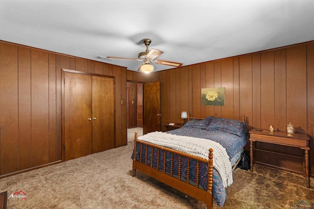 carpeted bedroom with ceiling fan, a closet, and wooden walls