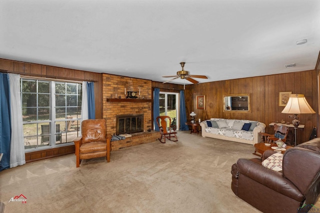 carpeted living room featuring a fireplace, ceiling fan, and wooden walls