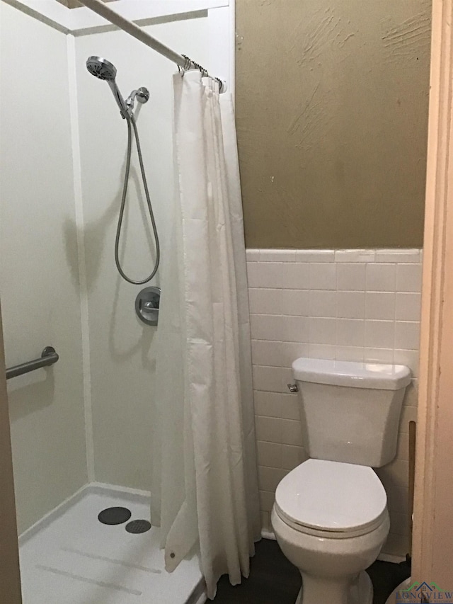 436 S Main St, Longview, TX 75601 - bathroom with a stall shower, a wainscoted wall, and tile walls