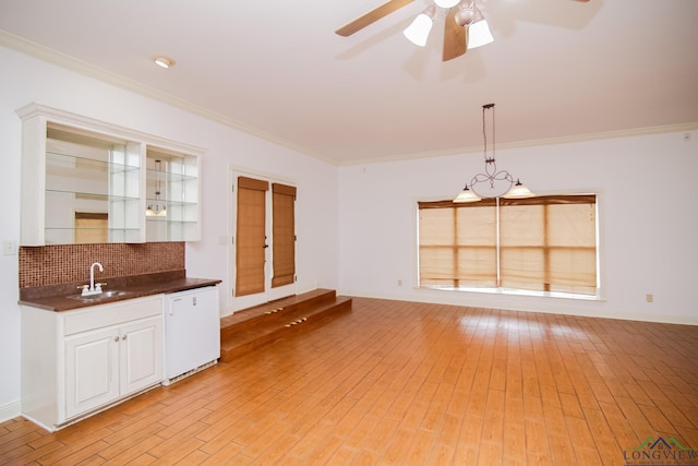 kitchen featuring tasteful backsplash, hanging light fixtures, crown molding, and sink