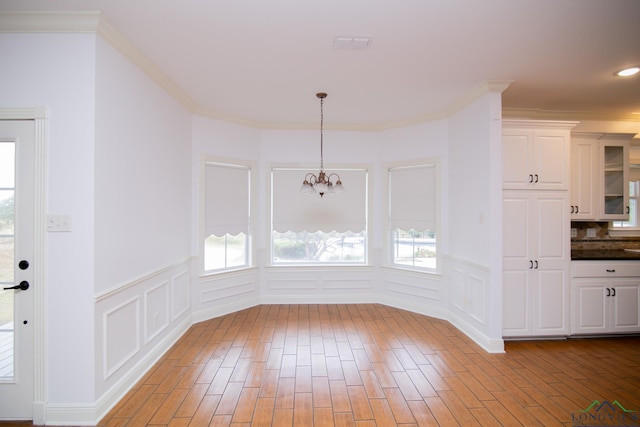 unfurnished dining area featuring ornamental molding, an inviting chandelier, and a healthy amount of sunlight