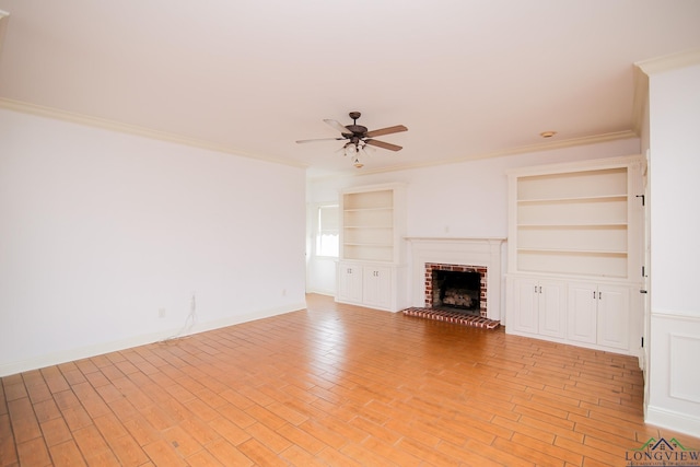 unfurnished living room featuring a brick fireplace, ceiling fan, built in features, and ornamental molding